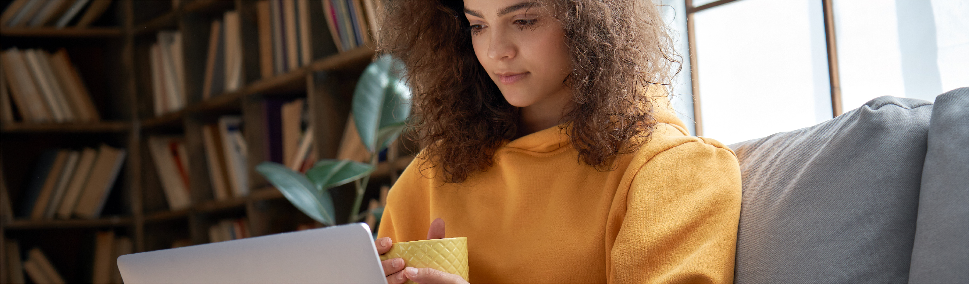 Young female college student in harvest gold sweater working on her computer.